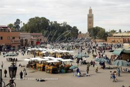 Image du Maroc Professionnelle de  Les calèches de jus d'orange sont bien alignés sur La mythique place Jemaa El Fana, avec ses charmeurs de serpents, lieu incontournable de Marrakech, la ville touristique du Maroc, Dimanche 27 Février 2005, au fond le minaret de la Koutoubia. (Photo / Abdeljalil Bounhar)